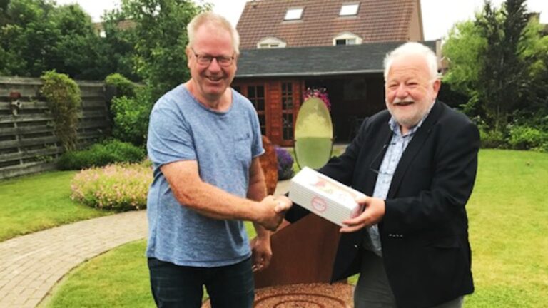 Voorzitter Bert Kolk biedt vrijwilliger gebak aan TV