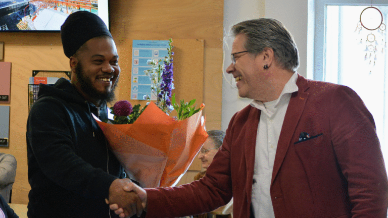 Offereins reikt bloemen uit aan Sherison, nieuw beschut BWRI